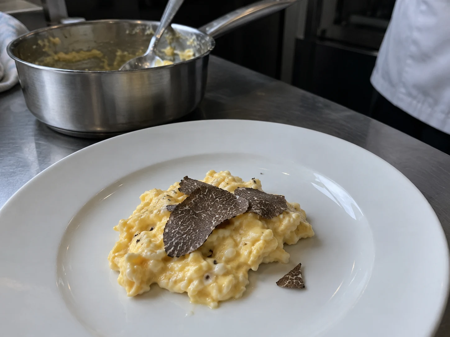 Brouillade fondante garnie de lamelles de truffe noire sur une assiette blanche
