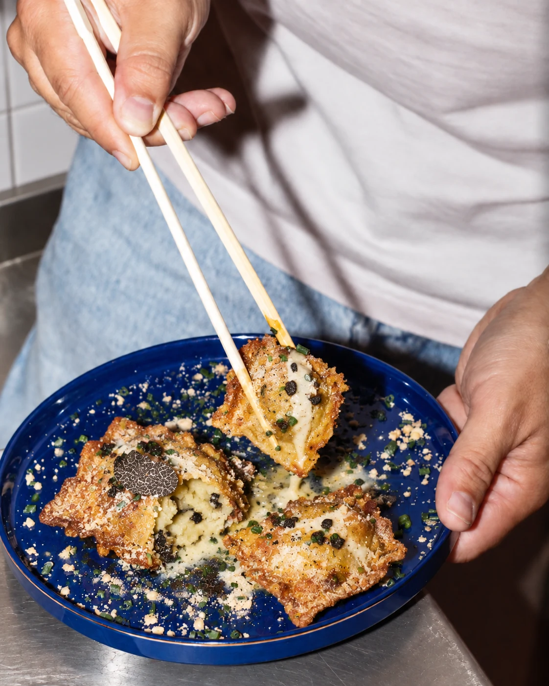 Bouchées croustillantes à la truffe dans une assiette bleue, dégustées avec des baguettes
